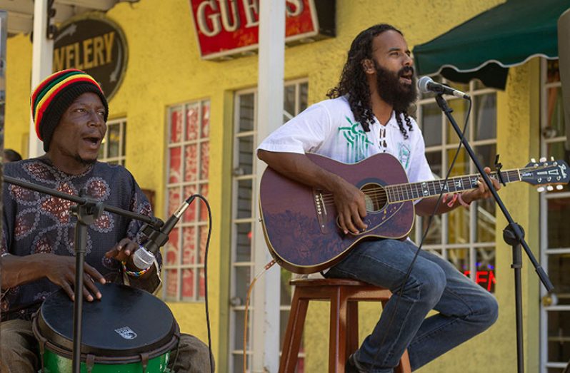 A drummer and a guitarist performing together at an outdoor event